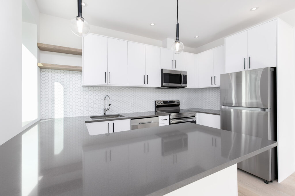 Open-Concept Kitchen Modern open-concept kitchen with white Caesarstone countertop and navy cabinetry by CanWest Cabinetry