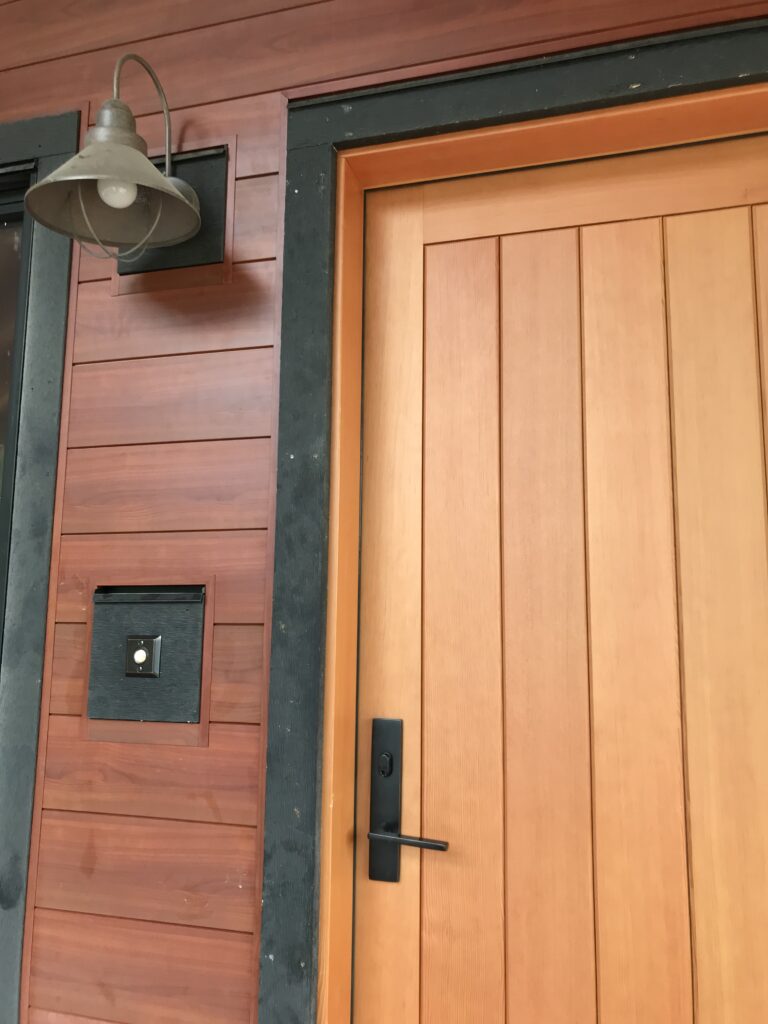 Close-up of the entry door's wood grain and matte black hardware