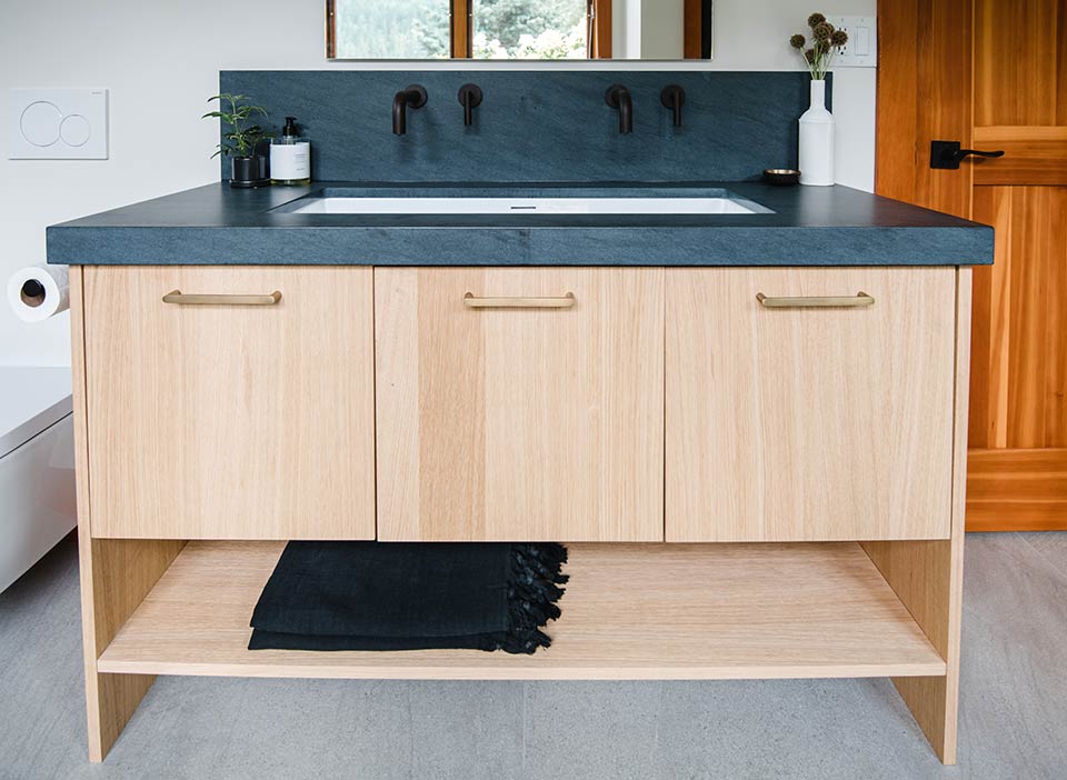 Custom bathroom vanity with matte black wall-mounted faucet and stone countertop at Cedar Estates renovation