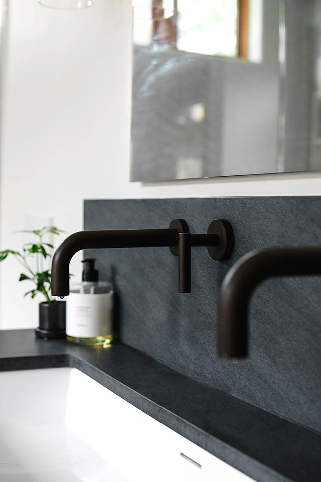 Black wall-mounted bathroom faucet and stone backsplash at Cedar Estates renovation