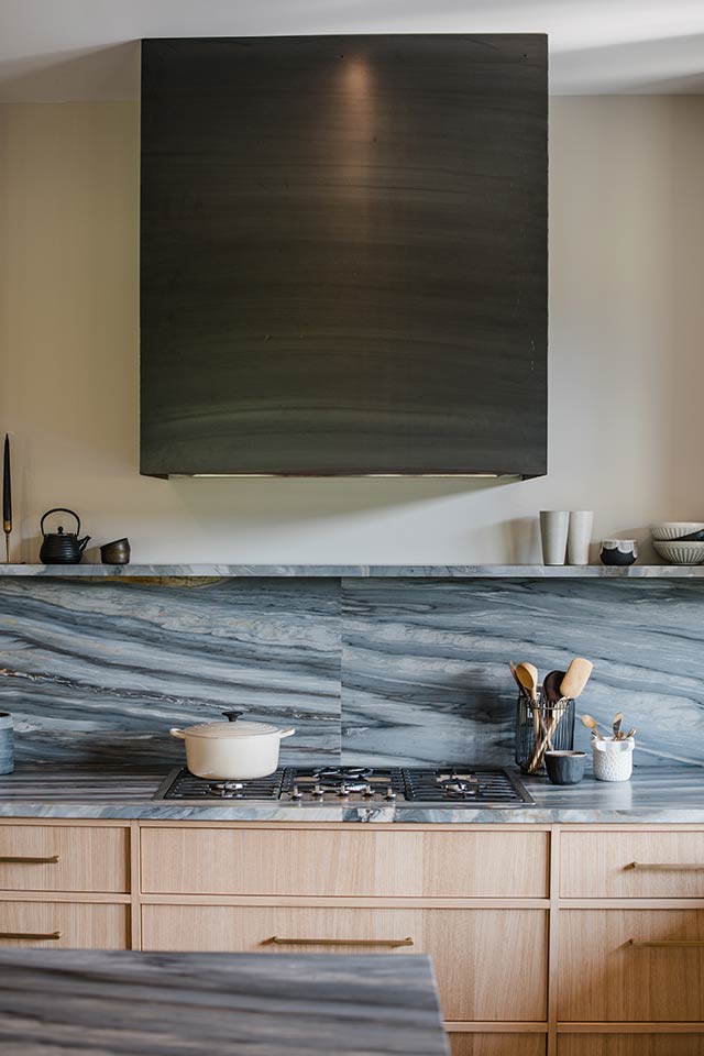 Wide view of modern kitchen renovation with custom hood vent and Calacatta Cielo countertops