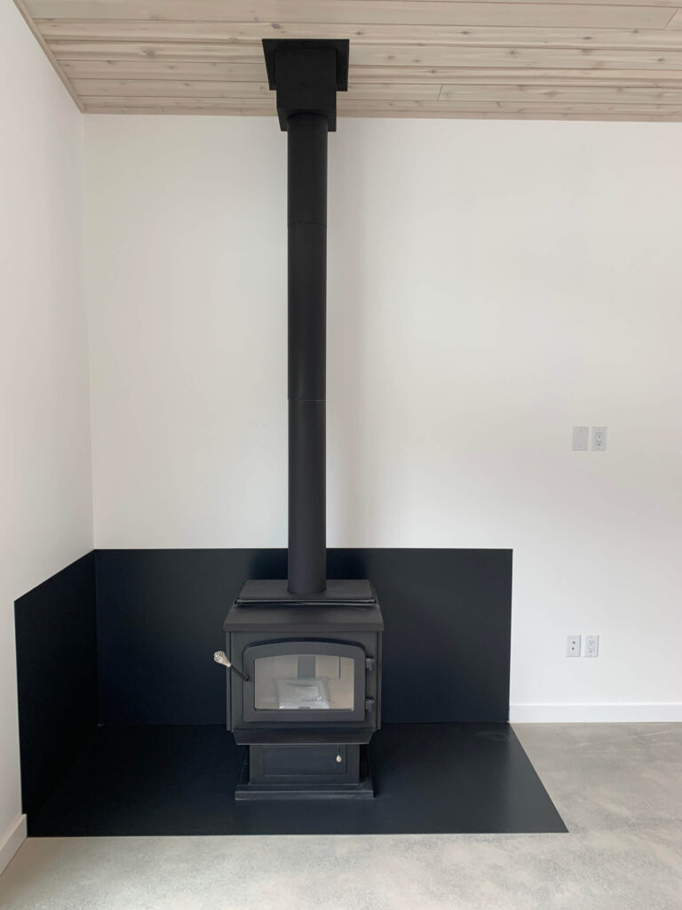 Freestanding woodstove installed in corner with modern finish