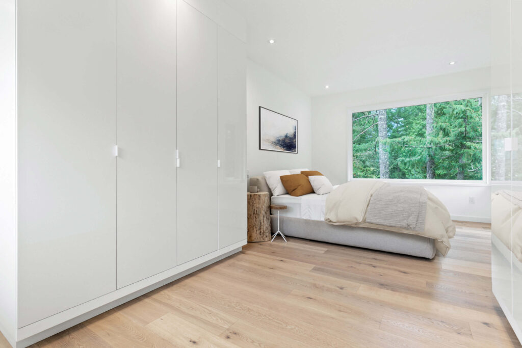 Modern primary bedroom with light flooring and large windows